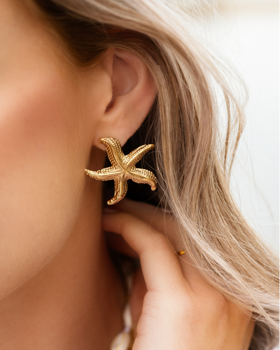 Model draagt gouden zeester oorbellen