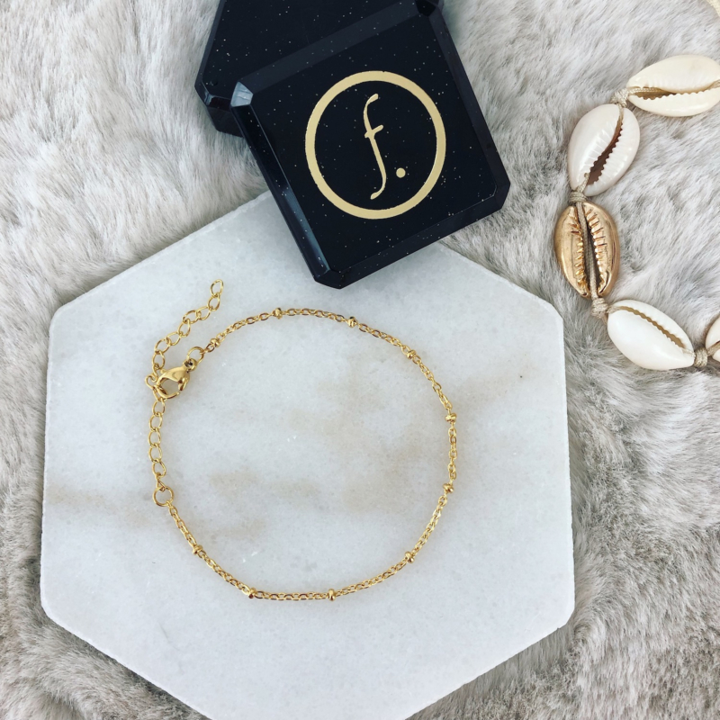 gouden armband met bolletjes op marmer