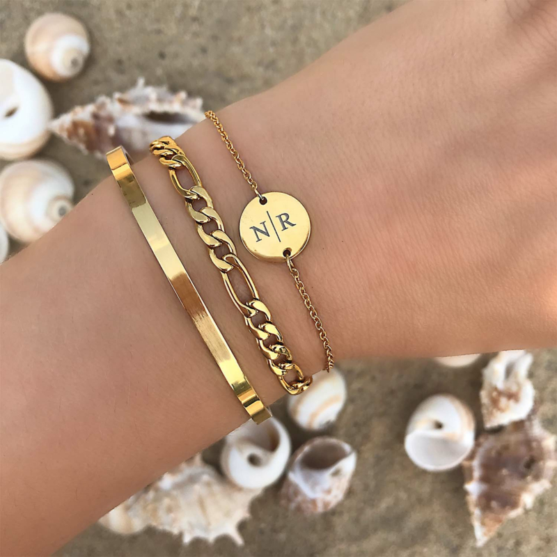 Gouden armbandjes om de pols met mix en match op het strand