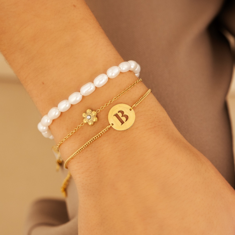 model draagt gouden armparty initials met parel armband