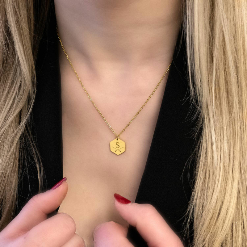 Vrouw met blonde haren draagt een letter ketting in het goud