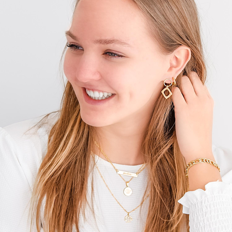 Gouden ketting met sierletters om de hals voor een complete look