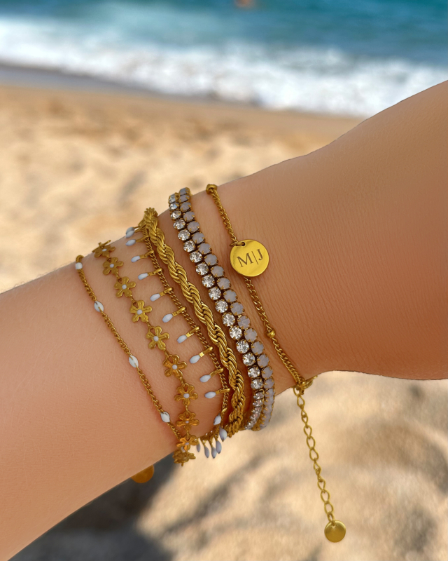 Model draagt gouden armbanden op strand