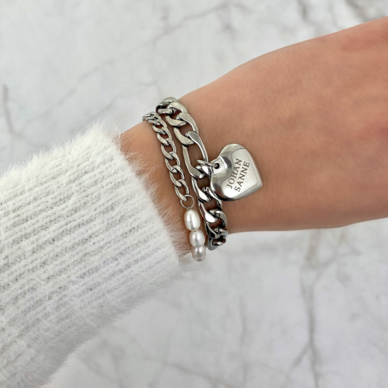 Trendy armparty met armbanden en een bedel op een witte trui