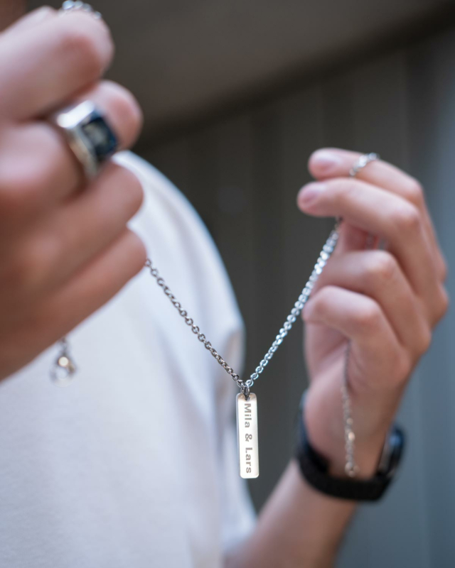 Het model draagt de zilveren mannen ketting met een gepersonaliseerde gravering