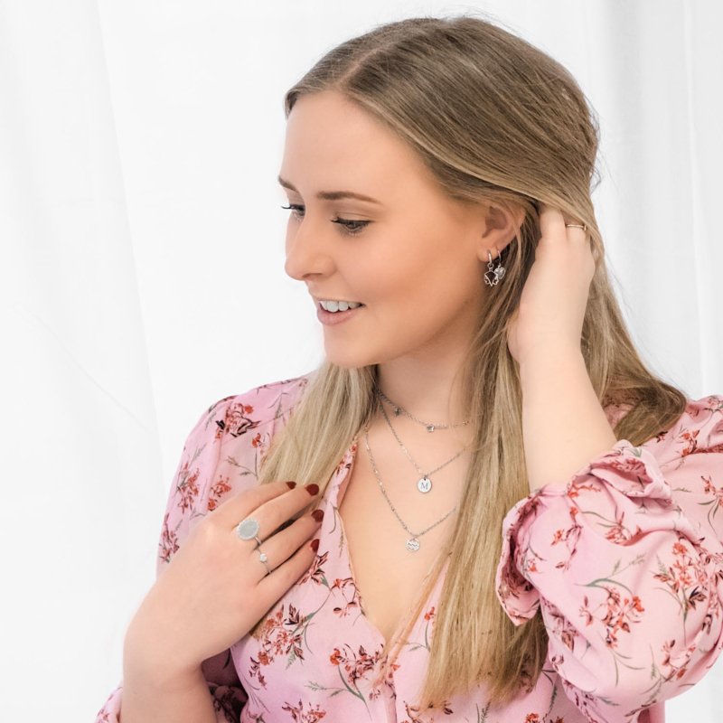 Vrouw met blonde haren draagt initial ketting in het zilver