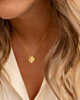 Model draagt gouden clover ketting