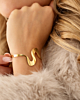 Gouden swirl bangle om pols