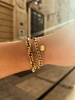 Model draagt gouden armbanden combinatie