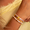 Model draagt mix van witte en gouden armbanden