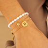 model draagt gouden armparty initials met parel armband