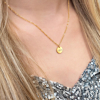 Gouden ketting met drie letters om de hals