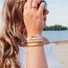 Gouden armbanden met roze touch op het strand