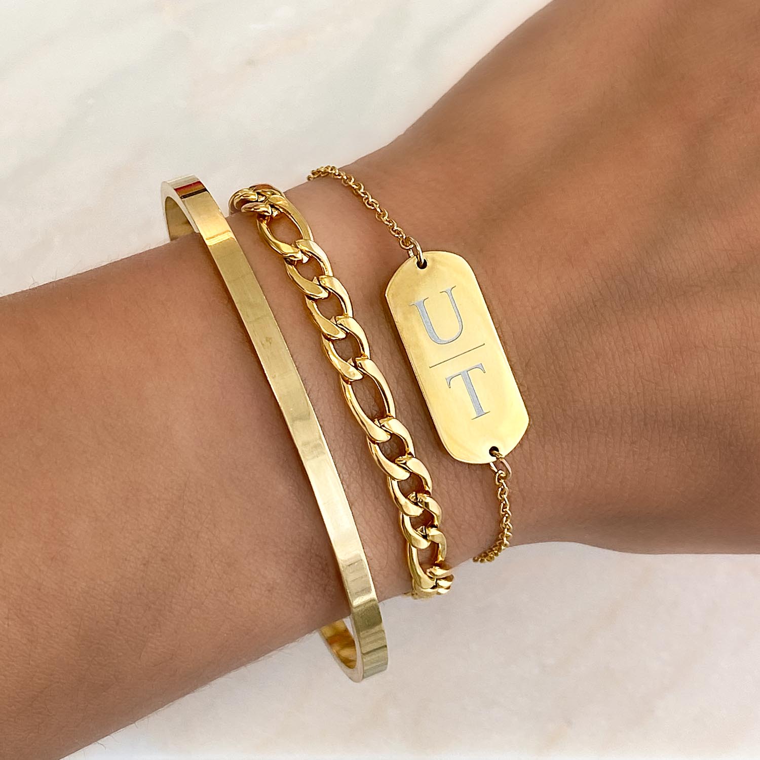 drie gouden armbanden met gravering bangle en schakelarmband