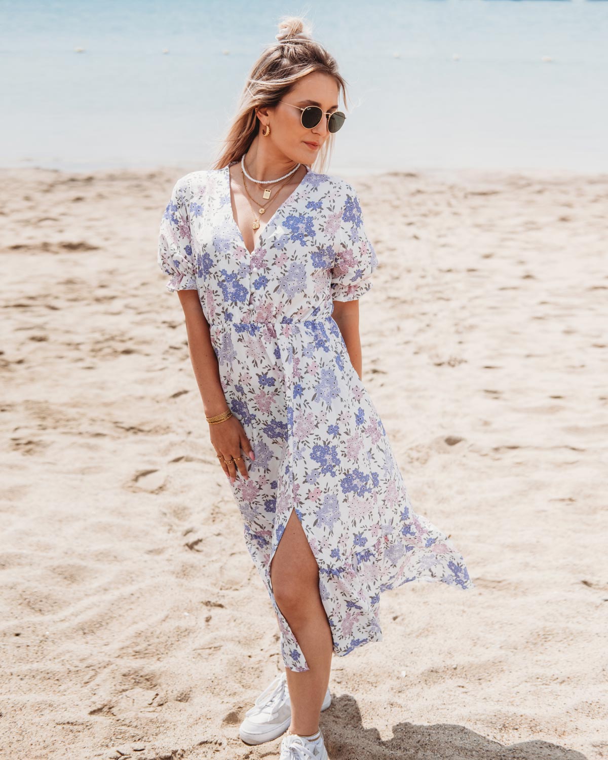 vrouw op strand draagt maxi jurk met bloemen